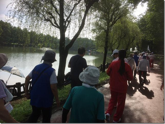 公園の中にある池の周りを男女が歩いている様子の写真